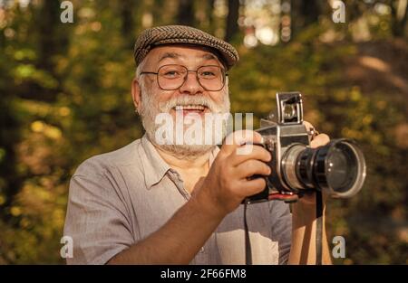 Fotocamera d'epoca. Noleggio fotografo vacanza. Ritratto di gioioso anziano uomo fare foto. Bel scatto. Retrò attrezzatura fotografica. Dire formaggio. DSLR Foto Stock