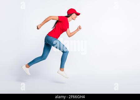 Foto laterale profilo a dimensione intera di giovane felice emozionato sorridente consegna ragazza che corre veloce in aria isolata sul colore grigio sfondo Foto Stock