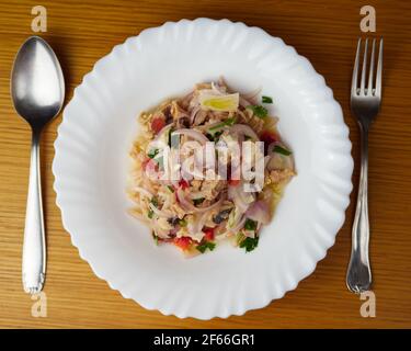 Nasello peruviano e ceviche intonate con verdure, spezie e lime in un piatto bianco con posate. Vista dall'alto Foto Stock