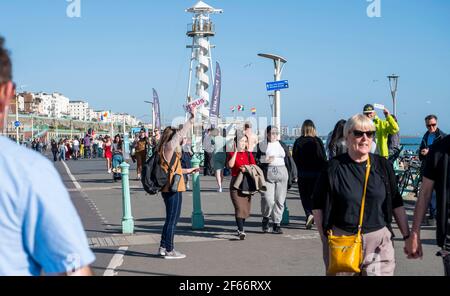 Brighton UK 30 marzo 2021 - il lungomare di Brighton è pieno di visitatori che affollano il mare il giorno più caldo dell'anno, con temperature che raggiungono la metà degli anni 20 centigradi in alcune parti del Sud-Est: Credit Simon Dack / Alamy Live News Foto Stock