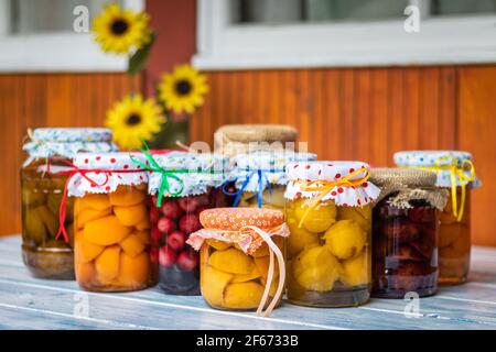 Composta di frutta fatta in casa sul tavolo, fuoco selettivo. Cibo biologico conservato in vasetti. Composta di pesche, albicocche, ciliegie, mele, pere e susine Foto Stock