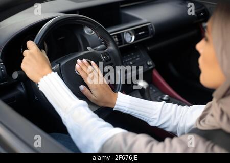 Donna musulmana seria che guida la sua auto e honking Foto Stock