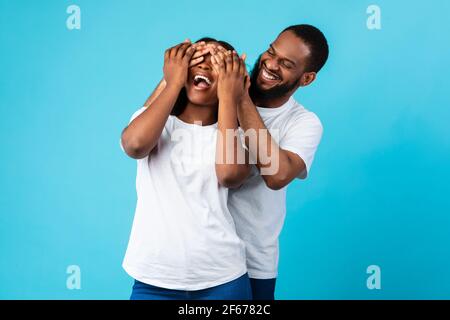 Felice uomo nero che fa sorpresa per la sua donna, coprendo gli occhi Foto Stock