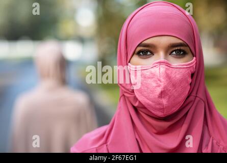 Arab Young Lady indossa una maschera protettiva che si posa all'aperto Foto Stock
