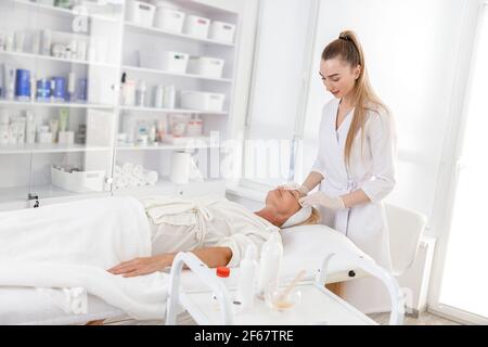 La donna anziana è sdraiata sulla schiena, ottenendo il massaggio di sollevamento del viso. Massaggio viso trattamento di bellezza Foto Stock