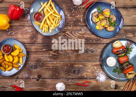 Disposizione piatta di patate bollite, patatine fritte, peperone, sale grosso, verdure grigliate su fondo di legno marrone. Copiare lo spazio. Foto Stock