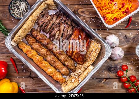 Shish Kebab e lula kebab sono messi in un contenitore. Consegna di cibo dai ristoranti. Foto Stock