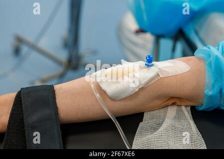 La mano del paziente sotto il IV è legata con un primo piano di bendaggio. Il concetto di fornire assistenza medica. Foto Stock