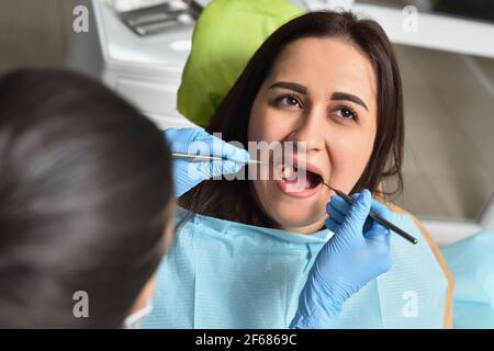 Dentista esamina i denti di una donna e cerca carie Foto Stock