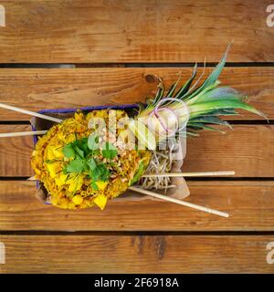 Riso fritto con gamberi servito in ananas su tavola di legno, cucina tailandese. Vista dall'alto Foto Stock