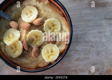 Mandorle e banana con in una ciotola di porridge di farina di mais su una superficie di legno Foto Stock