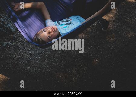 Tween Boy sale capovolte in un'amaca Foto Stock