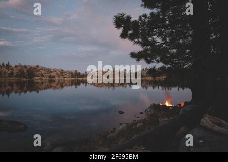 Falò brucia in un pit di pietra accanto ad un alpino Lago Foto Stock