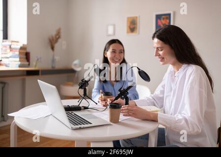 Giovane donna che registra podcast con un amico asiatico Foto Stock