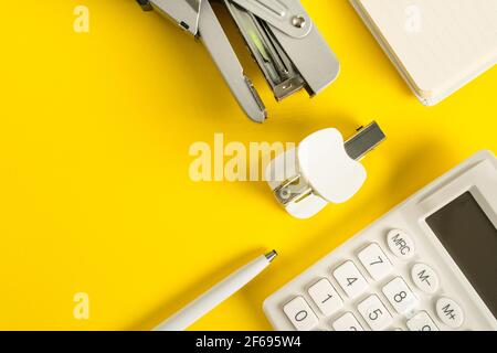 Accessori da ufficio su sfondo giallo, disposizione piatta gadget aziendali Foto Stock