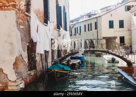 Lenzuola bianche che pendono fuori dalle finestre a cassettoni sopra il canale veneziano Foto Stock