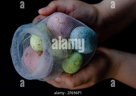 uova di pasqua in una rete, in mani, primo piano Foto Stock
