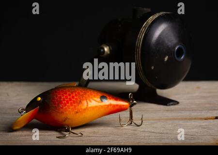 Vecchia esca di pesca e mulinello su superficie di legno. Foto Stock