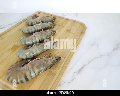Gamberi freschi su un tagliere di legno. Punti di messa a fuoco selettivi. Foto Stock