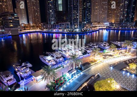 Vista aerea dei ristoranti e degli hotel, con i grattacieli illuminati e le navi da crociera attraccate catturate dal centro commerciale del porticciolo, Dubai Foto Stock