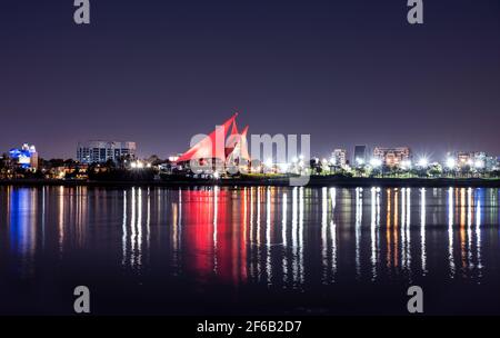 Vista panoramica del circolo illuminato a forma di vela del Dubai Creek Golf and Yacht Club dall'altra parte del Dubai Creek Park. Foto Stock