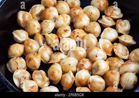 Deliziosi gnocchi fritti con carne in una padella primo piano Foto Stock