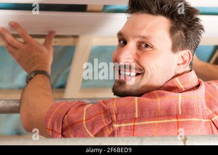 L'uomo facendo muretti a secco di lavorare sotto una pendenza del tetto Foto Stock