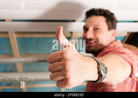 L'uomo facendo muretti a secco di lavorare sotto una pendenza del tetto Foto Stock