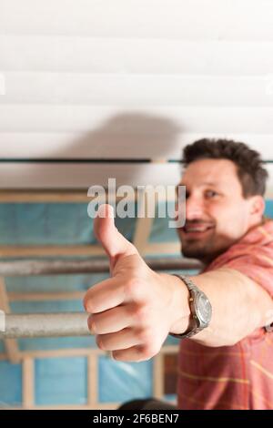 L'uomo facendo muretti a secco di lavorare sotto una pendenza del tetto Foto Stock