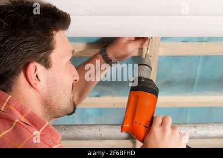 L'uomo facendo muretti a secco di lavorare sotto una pendenza del tetto Foto Stock