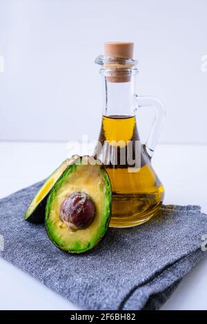 Caraffa di olio naturale e avocado di hass fresco maturo. Preparare il cibo in cucina. Ingredienti. Concetto di cibo sano Foto Stock