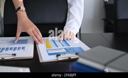 Un'immagine tagliata di due imprenditori che lavorano su un contabile documentale analizzano il reddito in ufficio. Foto Stock