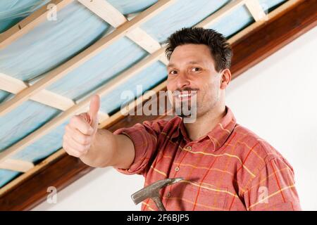 L'uomo facendo muretti a secco di lavorare sotto una pendenza del tetto Foto Stock