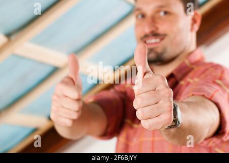 L'uomo facendo muretti a secco di lavorare sotto una pendenza del tetto Foto Stock