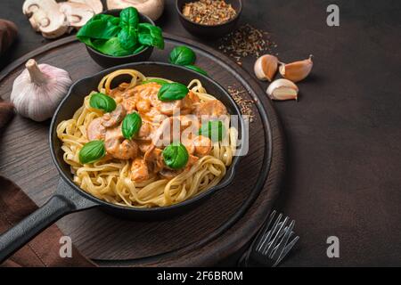 Pasta cremosa di funghi con aglio e basilico su sfondo marrone scuro. Foto Stock
