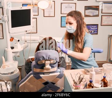 Dentista femminile che esamina i denti della donna in studio dentistico. Foto Stock