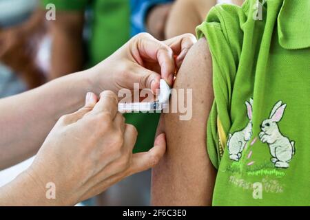 Il medico o l'infermiere indossano guanti bianchi medici utilizzando una siringa per ago per prelevare un campione di sangue dal braccio del paziente in ospedale. Foto Stock