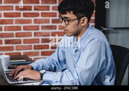 Imprenditore asiatico di Woking con il computer portatile e il foglio di lavoro sulla scrivania in ufficio.workflow digitale business online il concetto di stile di vita Foto Stock