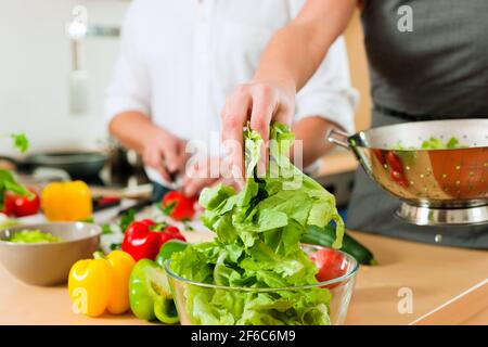 L uomo e la donna in cucina - essi preparare le verdure e insalate per pranzo o cena Foto Stock