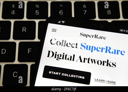 Sito Web SuperRare Digital Artworks visualizzato sullo smartphone posizionato sul computer portatile. Super Rare è un mercato NFT per i creatori di vendere e acquistare non-fungibile Foto Stock