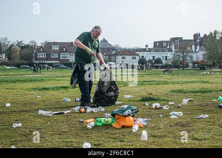 WIMBLEDON LONDRA, REGNO UNITO 31 MARZO 2021. Un operaio del merton council raccoglie i rifiuti su un sacchetto di bidone che include lattine di birra vuote e bottiglie di vino lasciate dai rivelatori su Wimbledon Common, in quanto le restrizioni di blocco sono state attenuate. Credit amer Ghazzal/Alamy Live News Foto Stock