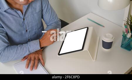 Ripresa tagliata di uomo freelance che tiene la penna stilo puntando sullo schermo del tablet digitale. Foto Stock