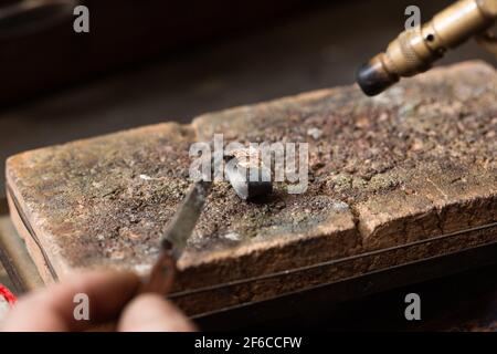 gioielleria orafa saldando un anello argentato sul banco da lavoro con una saldatura. Foto Stock