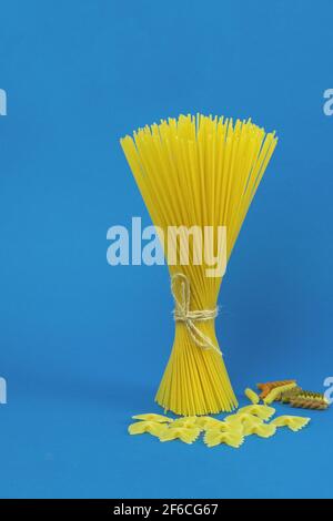 Spaghetti crudi e pasta su fondo blu. Spaghetti e pasta come sfondo con spazio per il testo. Pasta italiana su sfondo blu come bianco Foto Stock