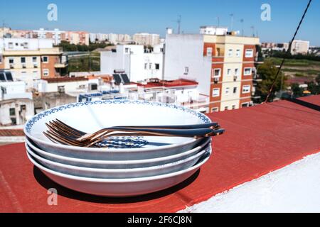 Piatti impilati con posate sulla terrazza Foto Stock