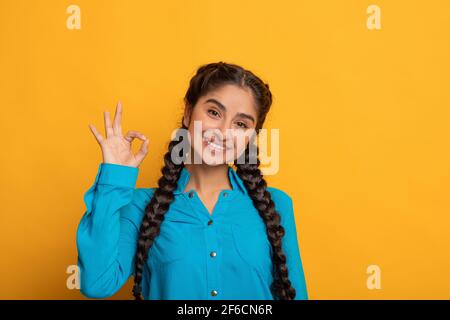 Felice donna insiana gesturing ok segno e sorridente Foto Stock