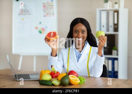 Giovane dietista femminile che tiene mela e pompelmo alla clinica di perdita di peso, spazio di copia Foto Stock