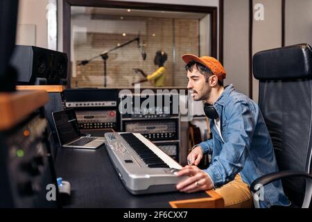 Foto d'inventario di un produttore di musica maschile che lavora con il cantante nero in uno studio di musica cool. Foto Stock