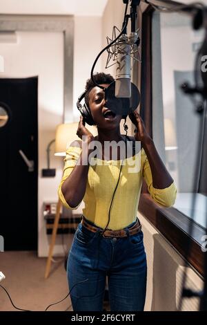 Foto d'inventario di una bella donna nera che canta e usa il microfono in studio musicale. Foto Stock