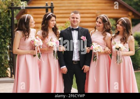 Bel groom stand vicino bella sposa con bouquet Foto Stock